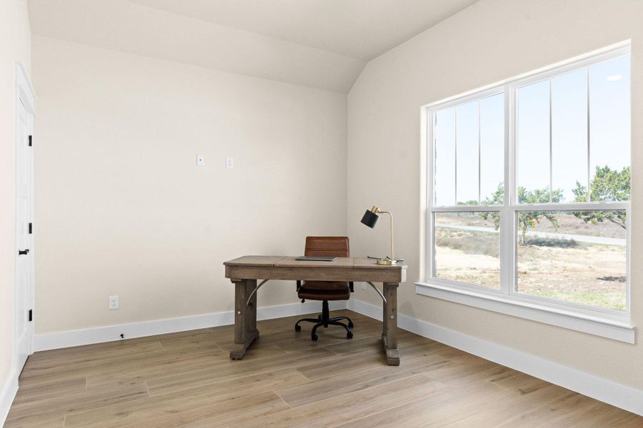 Office area featuring light wood finished floors, vaulted ceiling, and baseboards Office area featuring light wood finished floors, vaulted ceiling, and baseboards