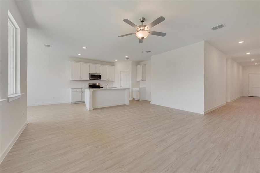 Unfurnished living room with ceiling fan and light hardwood / wood-style floors