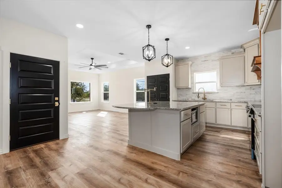 Kitchen view from hall way. Island has microwave and built in trash cabinet. Door to garage. Kitchen view from hall way. Island has microwave and built in trash cabinet. Door to garage.