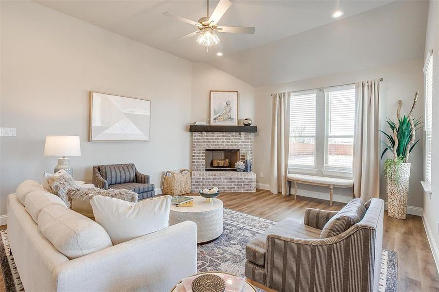 Living room with ceiling fan, light hardwood / wood-style floors, a fireplace, and vaulted ceiling