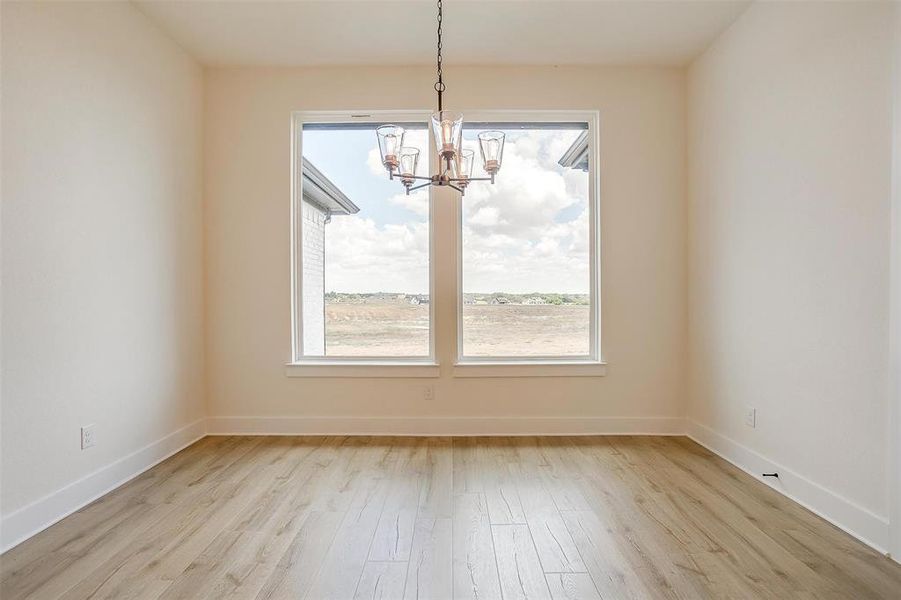 Unfurnished dining area with light hardwood / wood-style flooring and an inviting chandelier