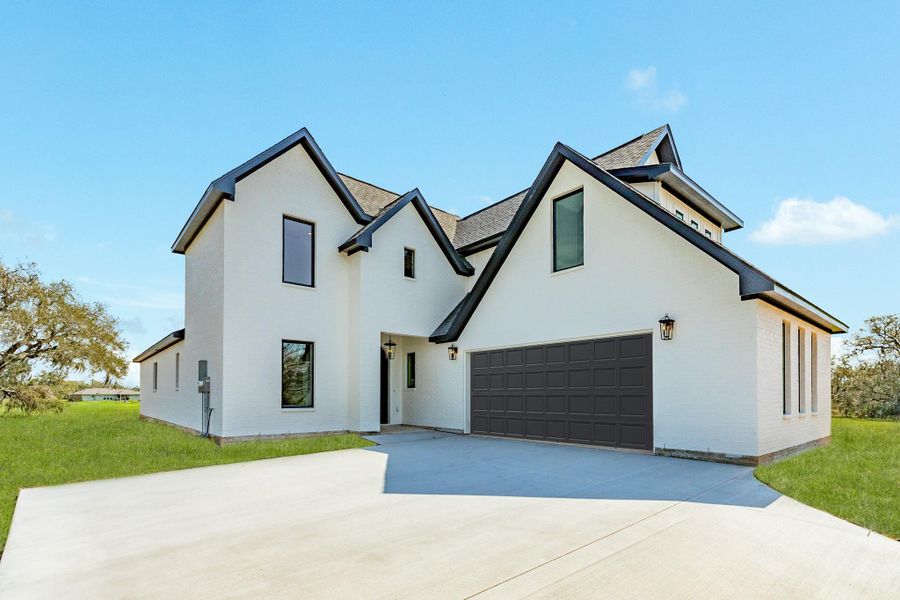 The elevation of this home offers a stunning view as you pull into the drive way.  Boasting black windows, white painted brick exterior, and a spacious drive way.