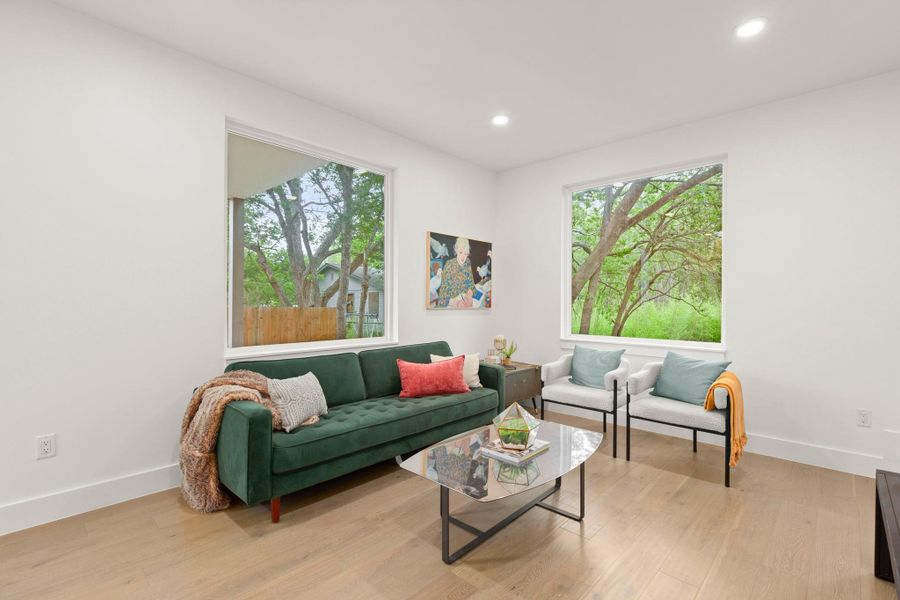 Bright living area featuring light wood-finish flooring, recessed lighting, and expansive windows