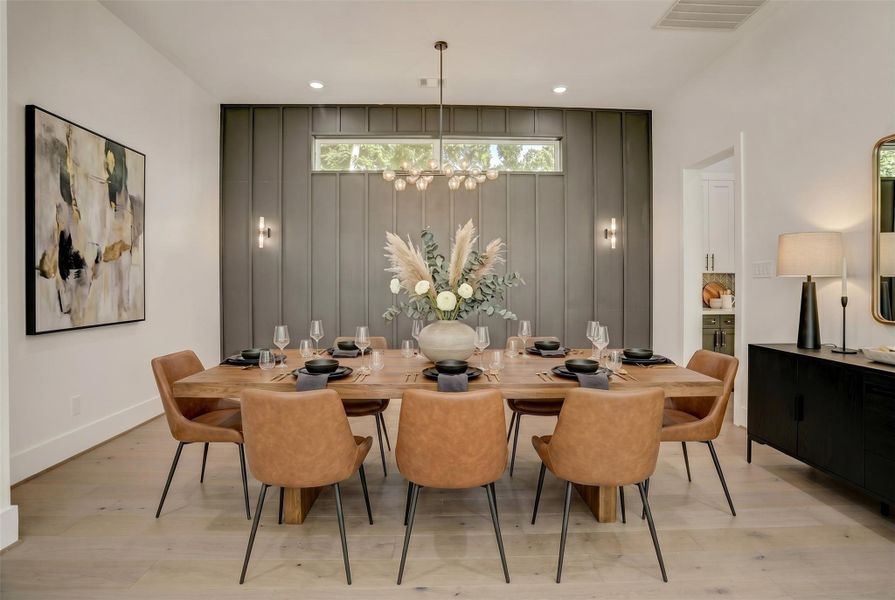 Open to the living room, the dining area with an accent wall and designer lighting offers a designated space to break bread. Virtually staged photo. Open to the living room, the dining area with an accent wall and designer lighting offers a designated space to break bread. Virtually staged photo.