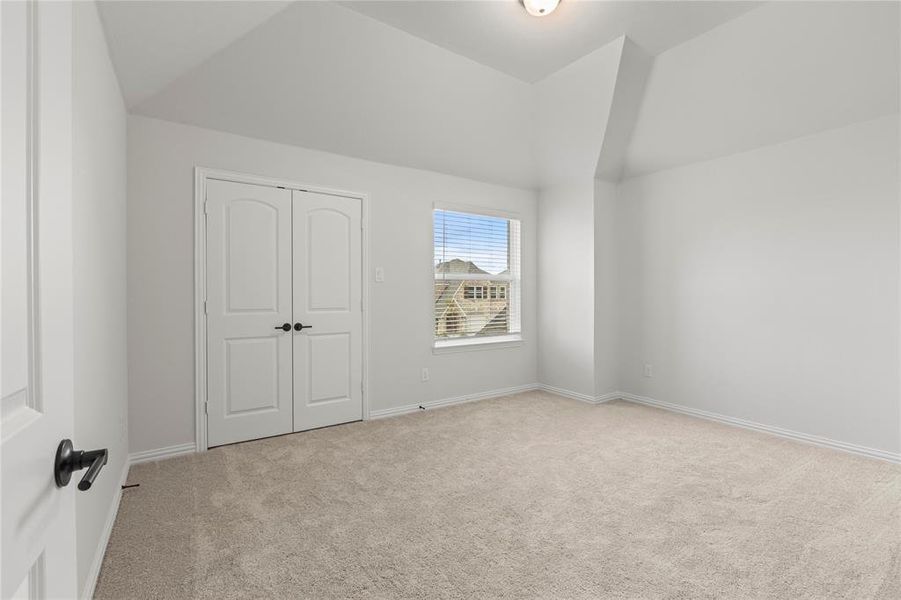 Unfurnished bedroom featuring lofted ceiling and light colored carpet