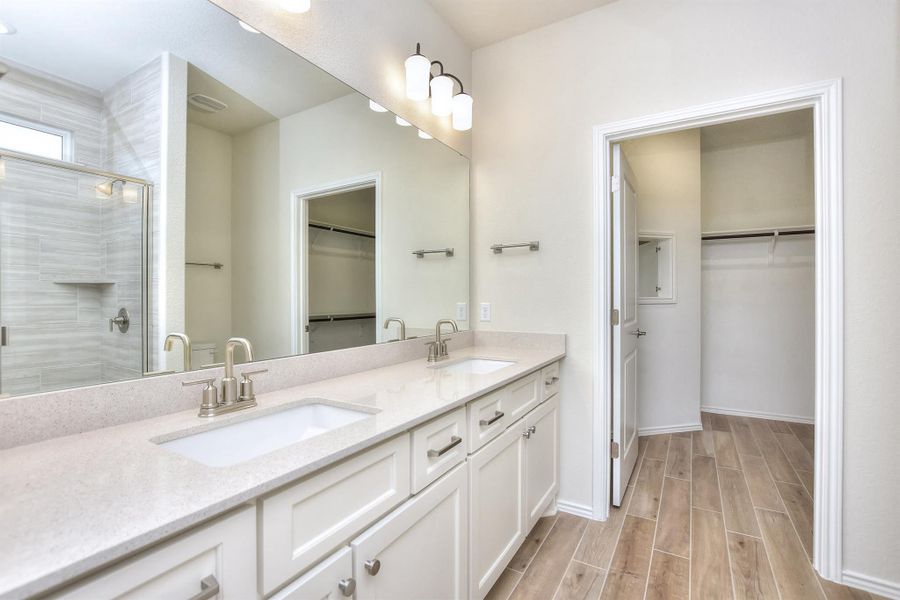 Full bathroom featuring wood tiled floor, double vanity, a stall shower, and a sink