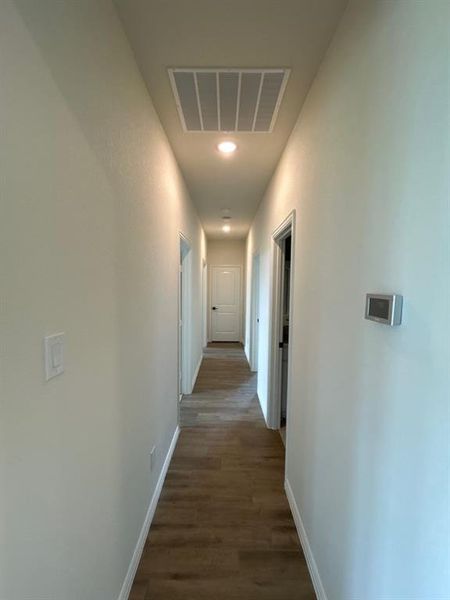Hallway featuring wood-finish flooring, recessed lighting, white trim, and a contemporary thermostat