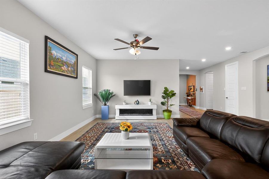 This living area features light-colored walls, a ceiling fan, and recessed lighting
