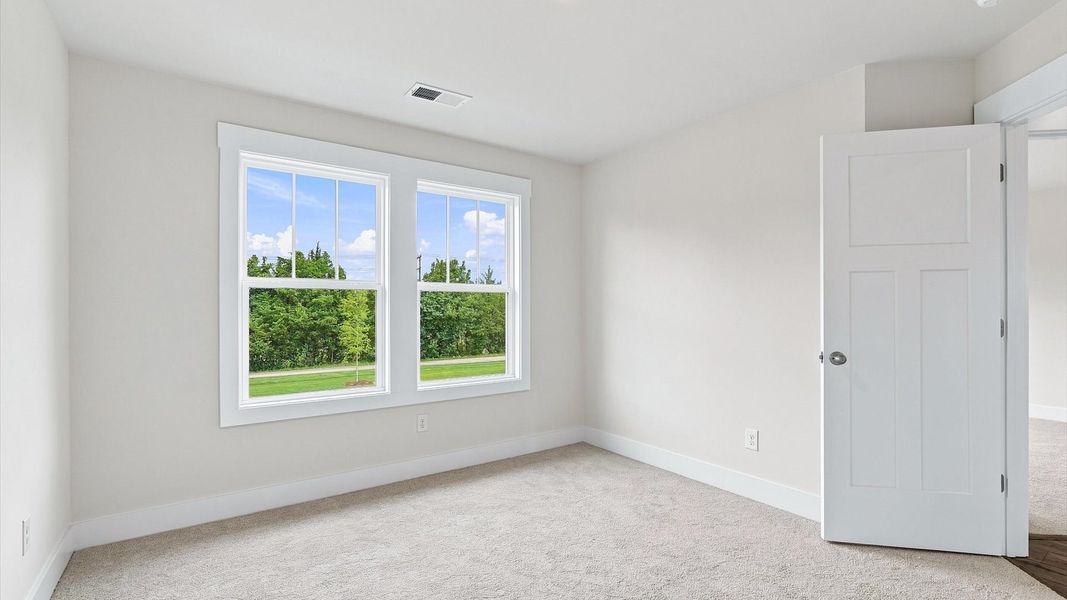 Elegant bedroom retreat featuring soft carpet and oversized windows that create a bright, welcoming space