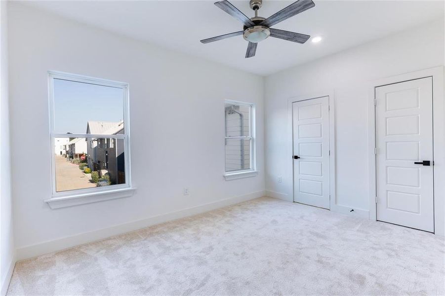 Unfurnished bedroom with ceiling fan and light carpet