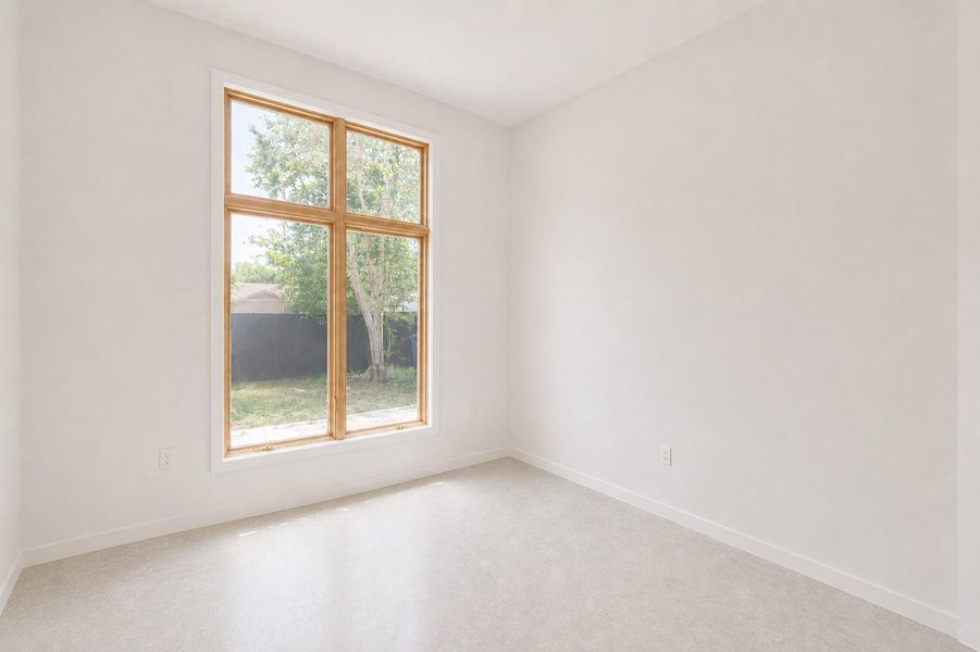 Room featuring a large wood-framed window, white walls, and light-toned flooring