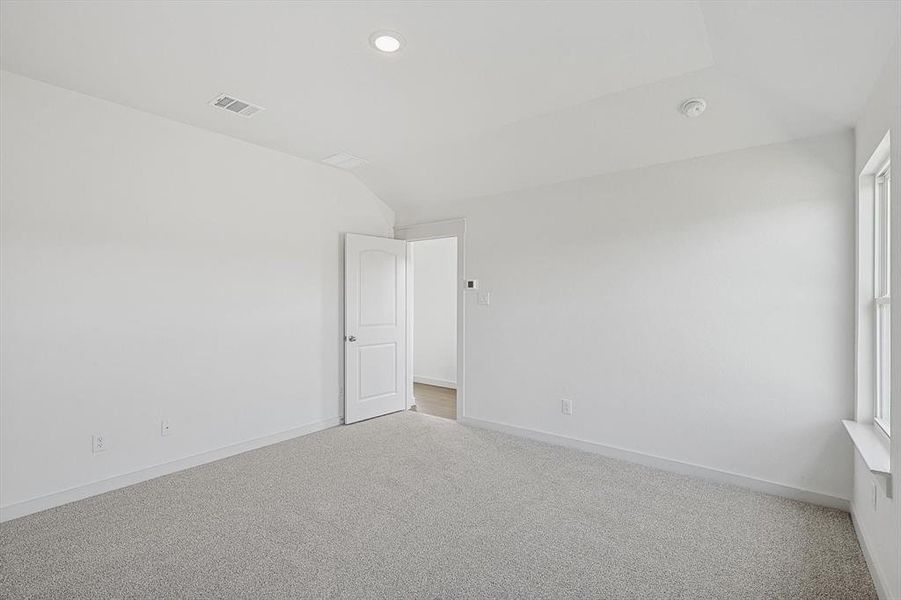 Carpeted empty room with lofted ceiling