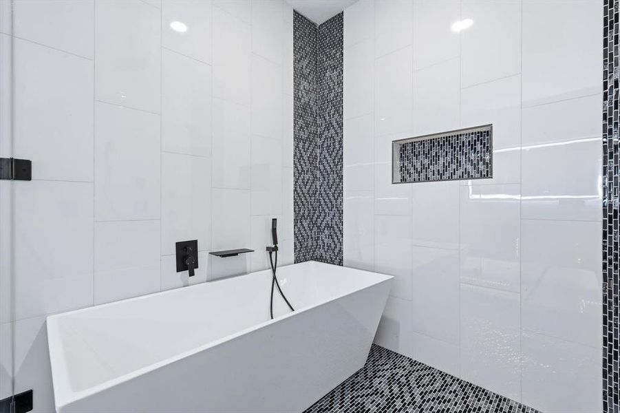 Bathroom featuring tile walls, a freestanding tub, and tile patterned flooring
