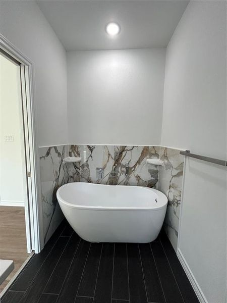 Bathroom with tile walls, wood-type flooring, and a bath