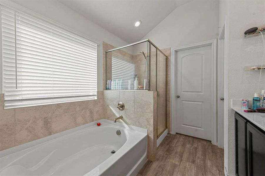 Bathroom featuring vanity, separate shower and tub, hardwood / wood-style floors, and vaulted ceiling