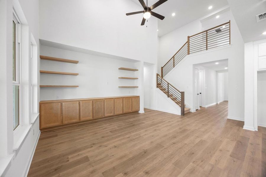 Unfurnished living room featuring a high ceiling, light wood-type flooring, a ceiling fan, recessed lighting, and stairway Unfurnished living room featuring a high ceiling, light wood-type flooring, a ceiling fan, recessed lighting, and stairway