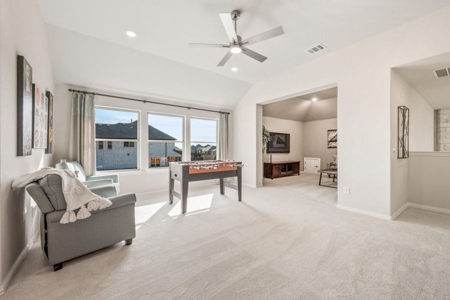 Spacious game room with foosball table, carpet flooring, ceiling fan, and vaulted ceiling open to media room Spacious game room with foosball table, carpet flooring, ceiling fan, and vaulted ceiling open to media room