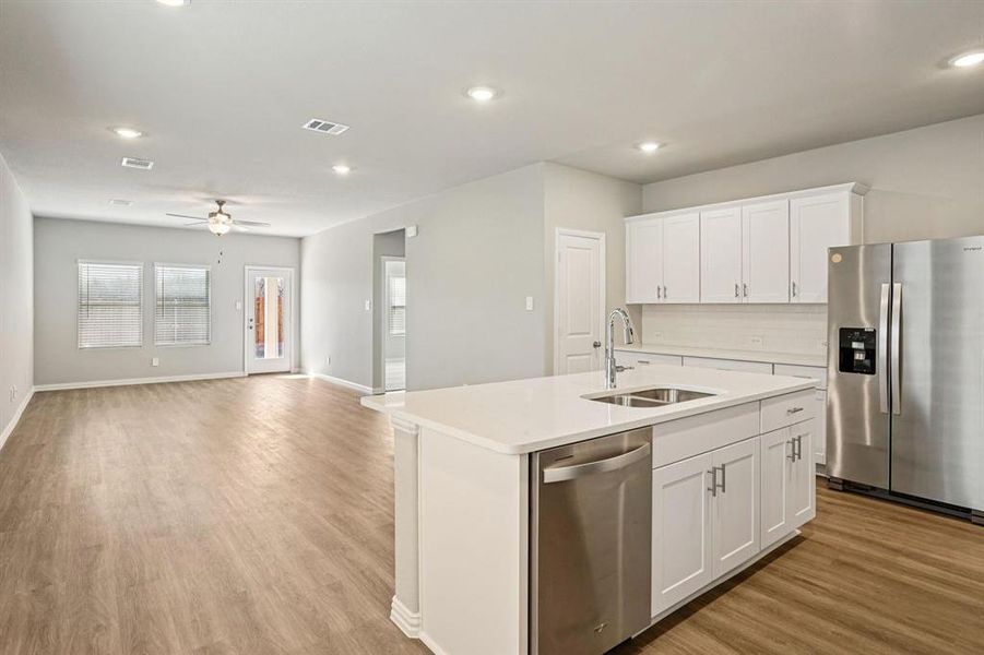Kitchen featuring stainless steel appliances, white cabinets, a kitchen island with sink, open floor plan, and recessed lighting