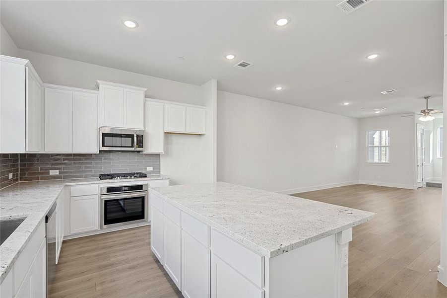 The kitchen features white cabinetry, granite countertops, and a gray tile backsplash