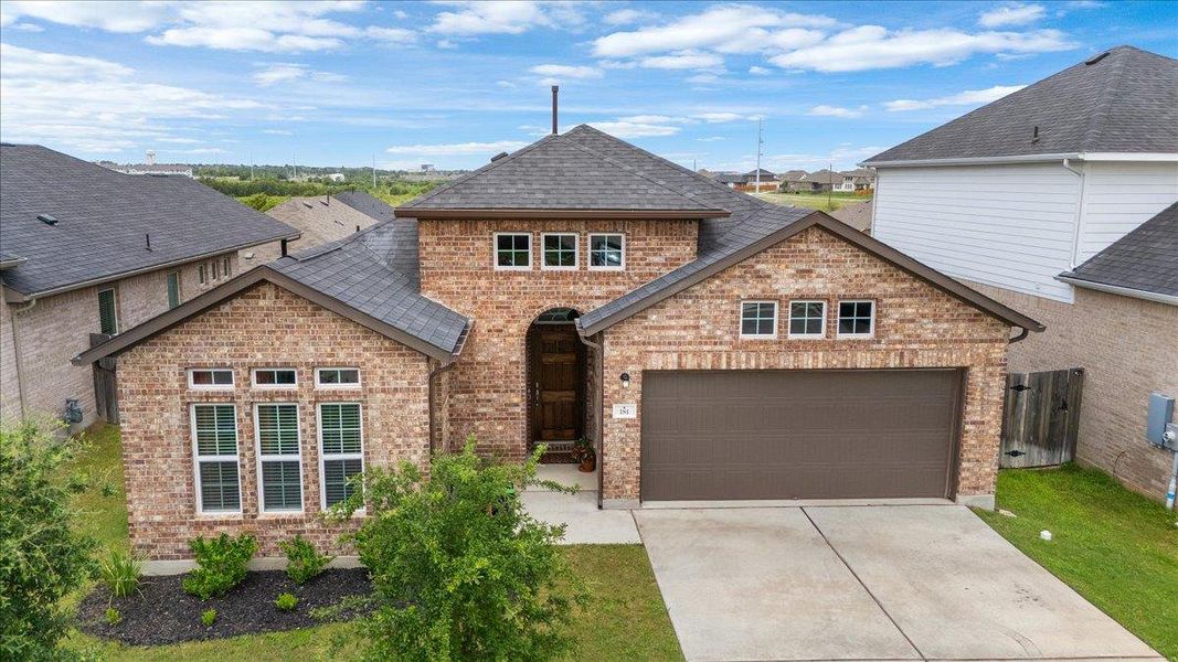 View of front of house with brick siding, driveway, and a garage