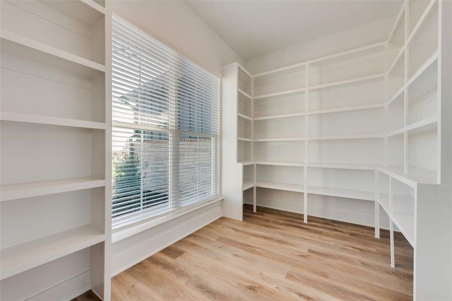 Bright room featuring extensive built-in shelving, a large window with blinds, and wood-finish flooring