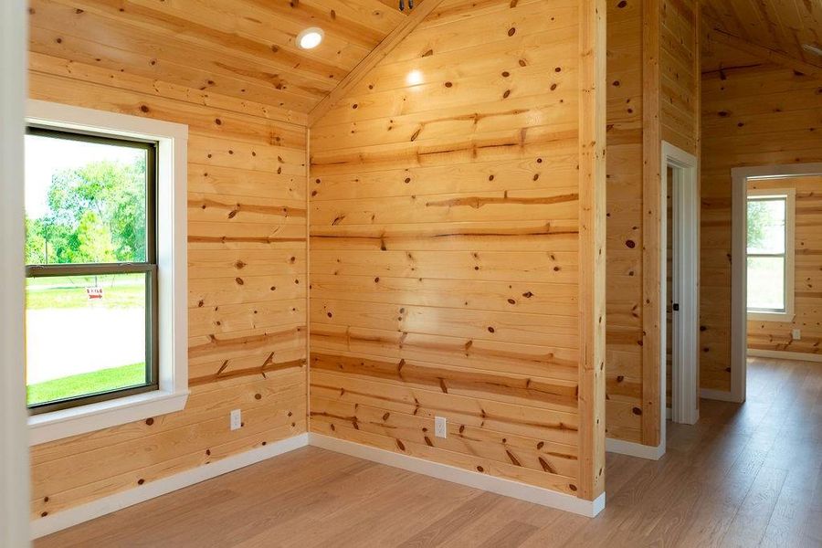 Additional living space featuring vaulted ceiling, light wood-type flooring, wood walls, and wood ceiling Additional living space featuring vaulted ceiling, light wood-type flooring, wood walls, and wood ceiling
