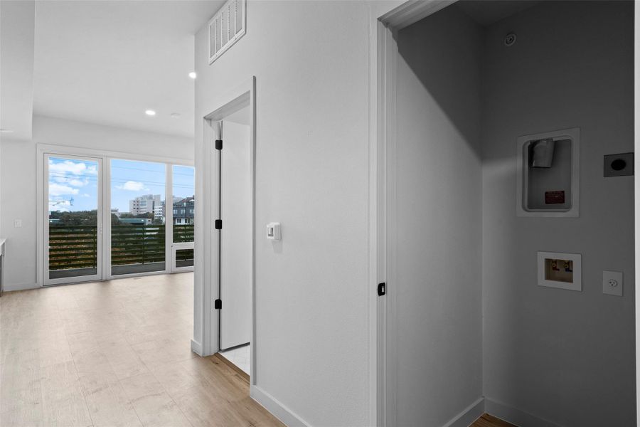 Corridor featuring light wood-style floors, baseboards, and visible vents