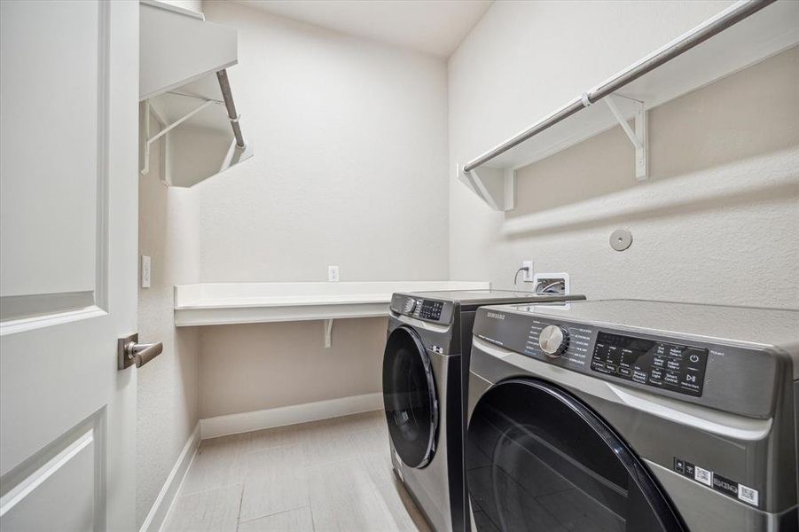 The laundry room is designed for convenience, accommodating full-size appliances. It also features a folding table, shelves for additional storage, and multiple clothes rods.