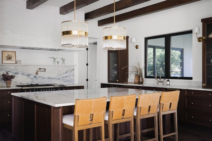 This light-filled kitchen is designed for high-end entertaining, anchored by a massive quartzite center island that serves as the natural gathering spot for daily life.