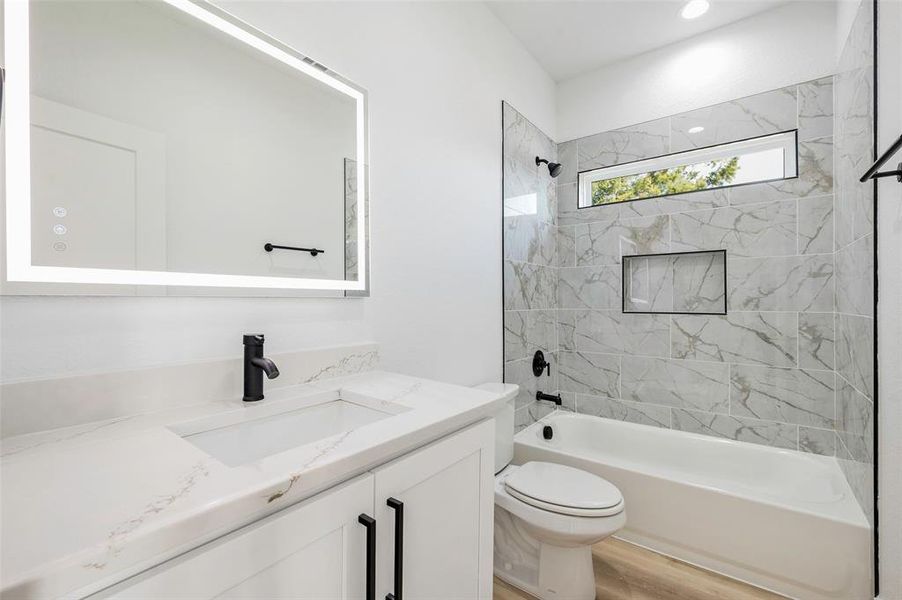 Full bathroom with toilet, hardwood / wood-style floors, vanity, and tiled shower / bath