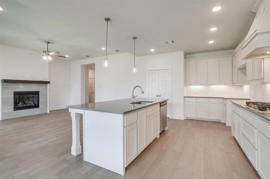 Kitchen featuring white cabinets, ceiling fan, a center island with sink, and light hardwood / wood-style flooring