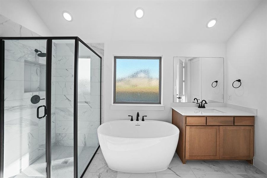 Full bath featuring light marble finish flooring, a freestanding tub, vanity, a shower stall, and recessed lighting Full bath featuring light marble finish flooring, a freestanding tub, vanity, a shower stall, and recessed lighting