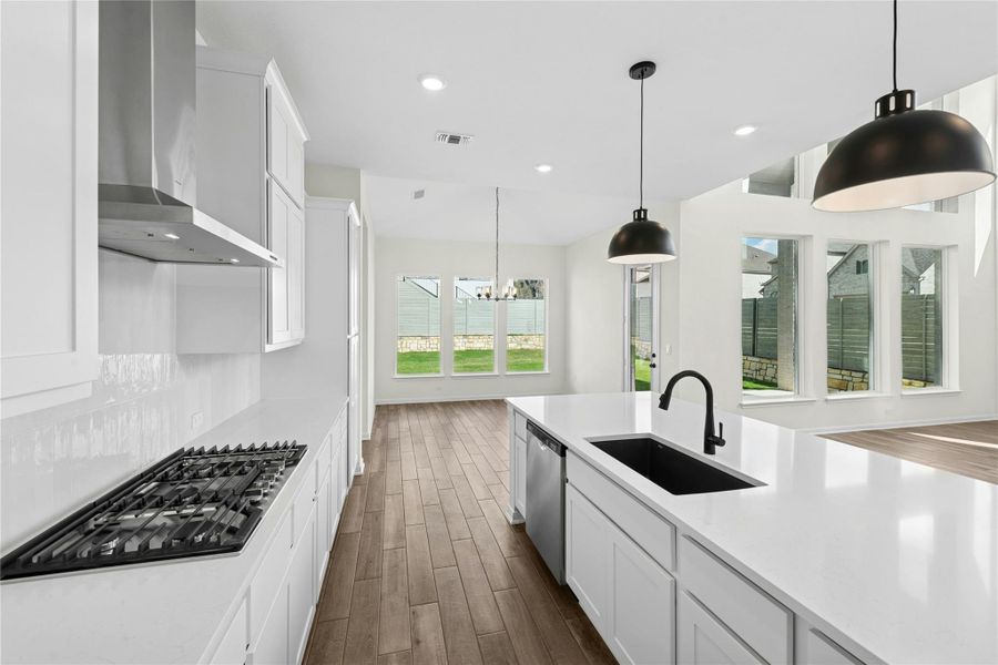 Kitchen featuring white cabinets, dark wood-style floors, decorative light fixtures, stainless steel appliances, and a chandelier Kitchen featuring white cabinets, dark wood-style floors, decorative light fixtures, stainless steel appliances, and a chandelier