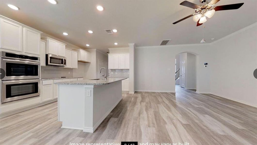 Kitchen featuring appliances with stainless steel finishes, a sink, ornamental molding, arched walkways, and ceiling fan