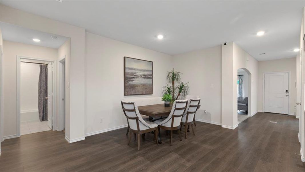 Dining room with arched walkways, dark wood-style flooring, and recessed lighting