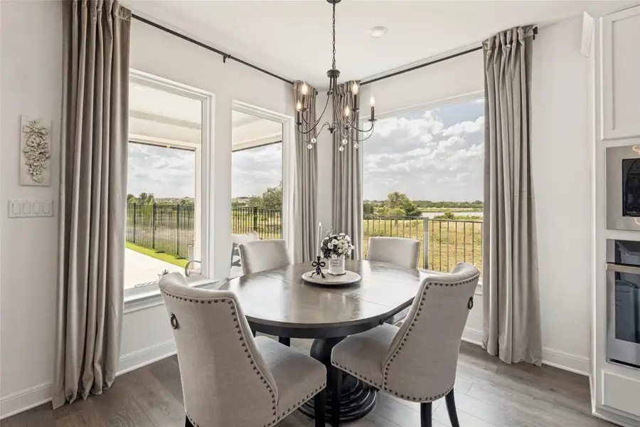 Large picture windows frame serene outdoor views in this inviting dining area with wood-look flooring.