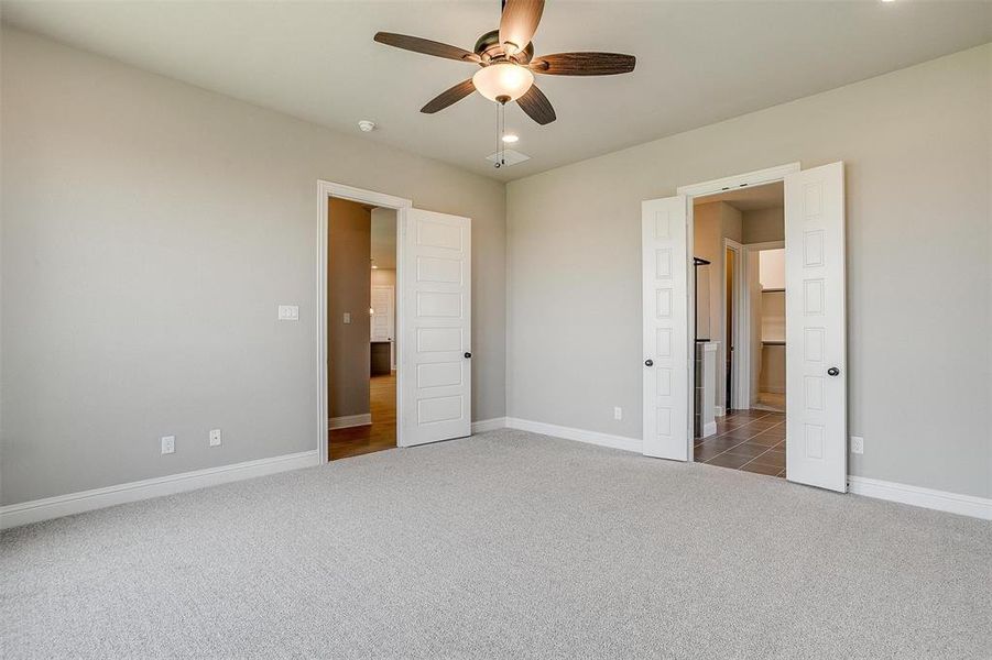 Unfurnished bedroom with dark colored carpet and ceiling fan