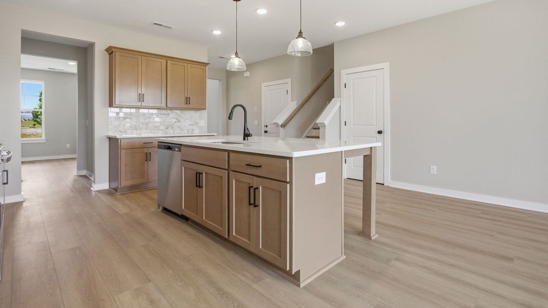 Kitchen with quartz countertops, tile backsplash, and nearby staircase Kitchen with quartz countertops, tile backsplash, and nearby staircase