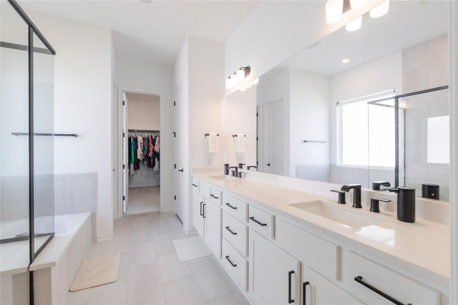 Full bathroom featuring a stall shower, double vanity, a spacious closet, and a garden tub