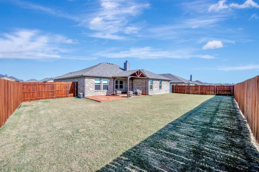 Back of house with a fenced backyard, a chimney, brick siding, and a patio