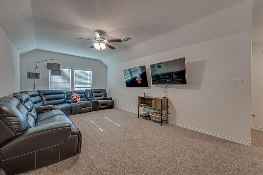 Carpeted living room with vaulted ceiling and ceiling fan