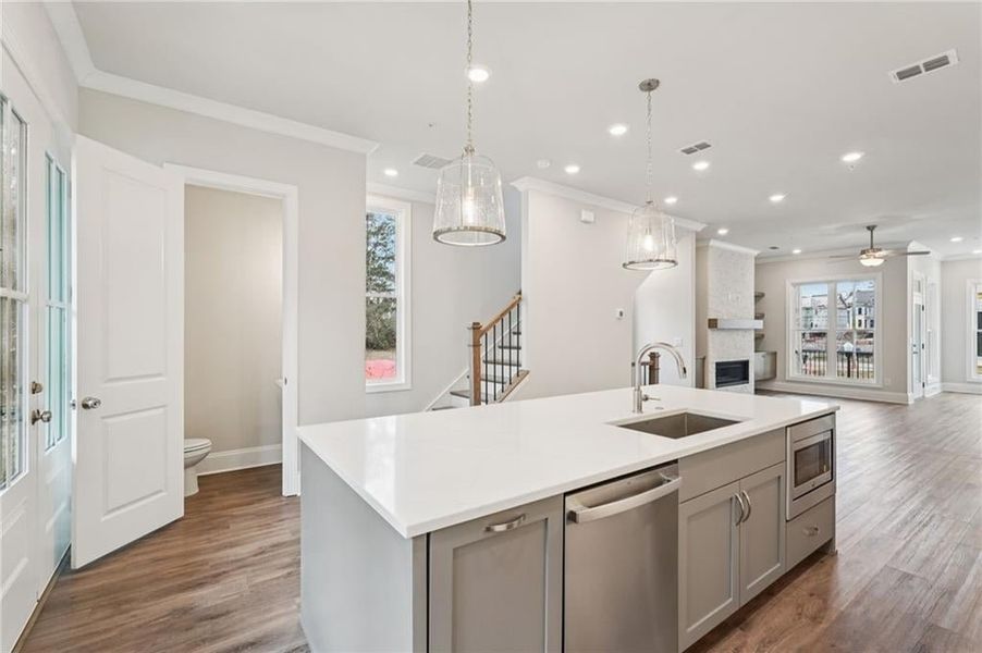Kitchen with gray cabinetry, stainless steel appliances, an island with sink, open floor plan, and crown molding
