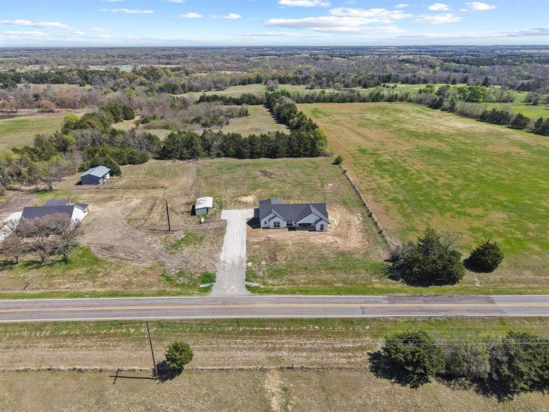 The property features a ranch-style home with an attached garage, a gravel driveway, and expansive surrounding land