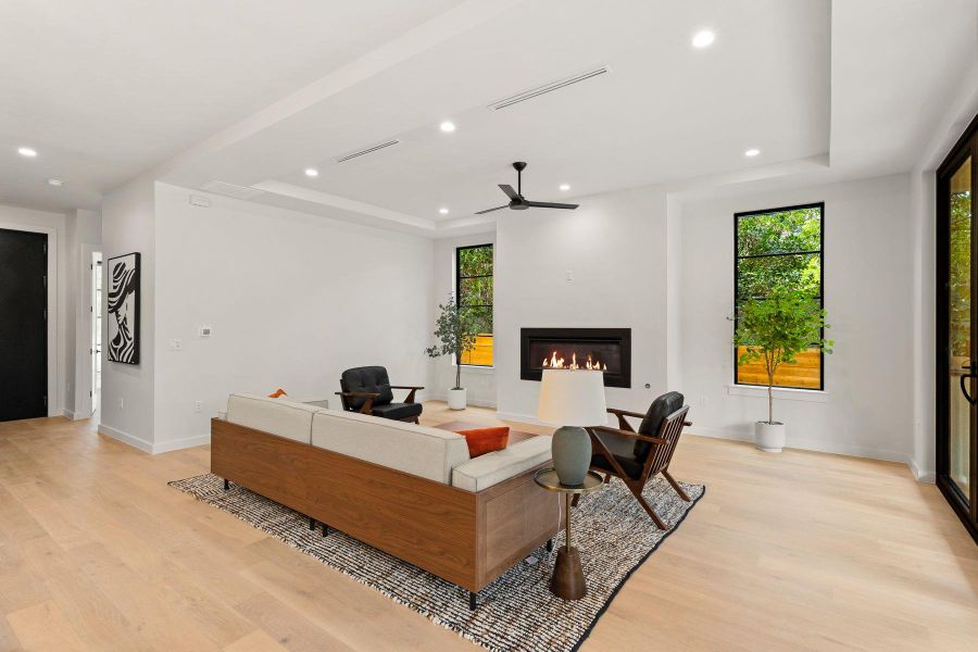 A modern fireplace anchors this living space accented by wood flooring and recessed lighting.