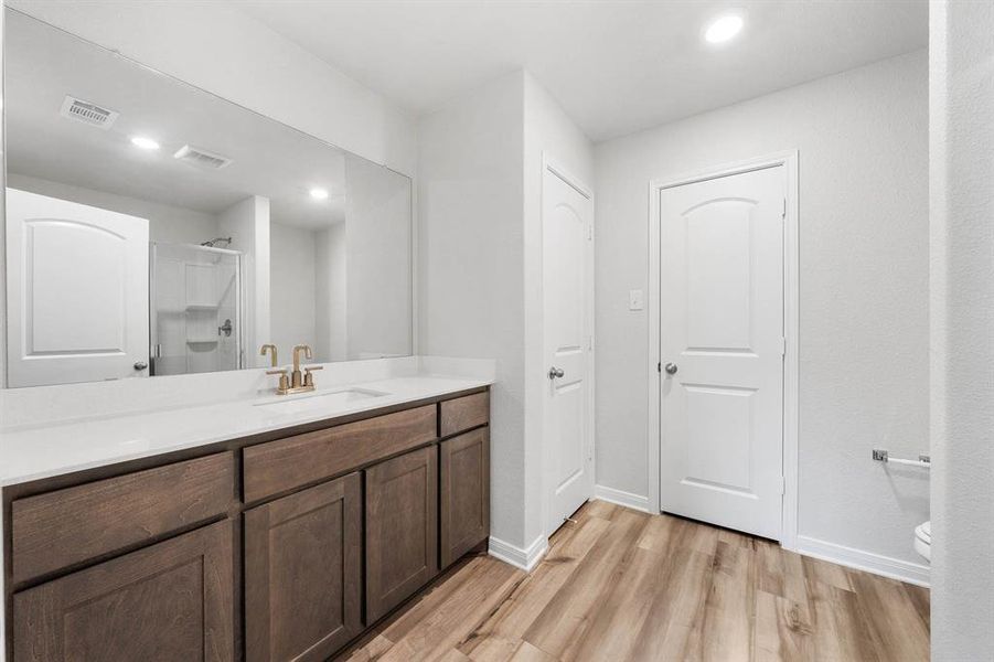 Bathroom with toilet, a shower with shower door, vanity, and hardwood / wood-style flooring