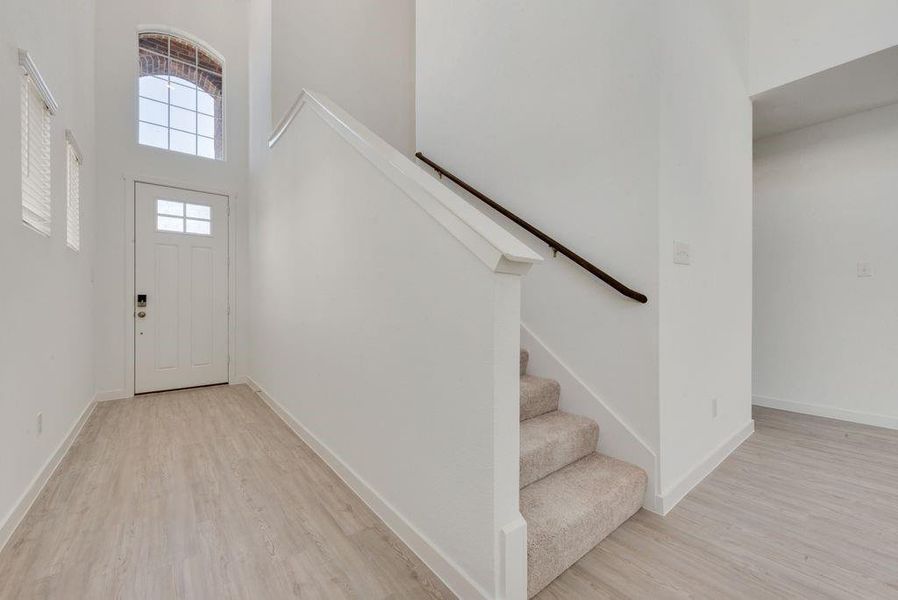 Foyer with wood finished floors, a towering ceiling, and stairs Foyer with wood finished floors, a towering ceiling, and stairs