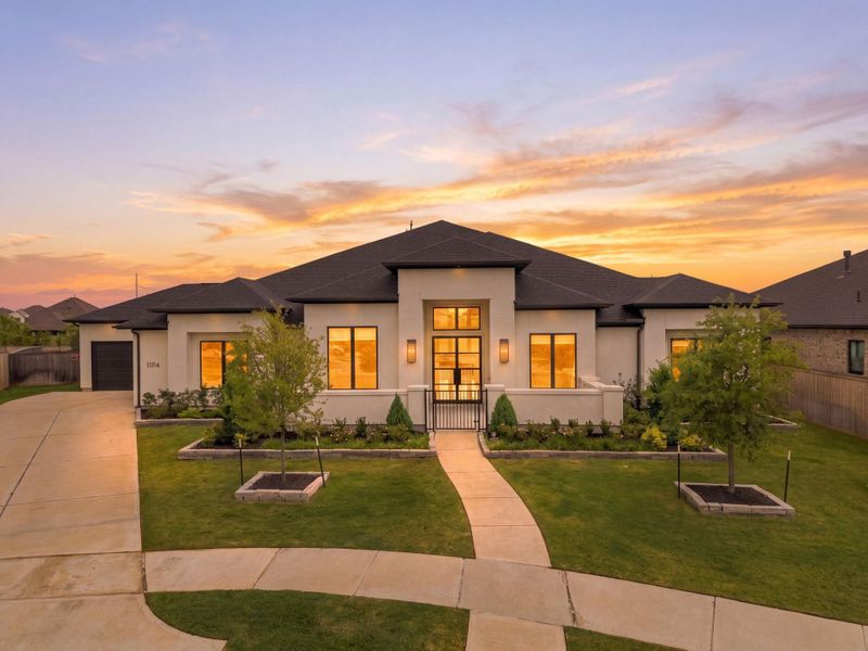 This nearly new Medici Plan by Fedrick Harris awaits in the master-planned community of Bridgeland, within Desert Marble. The rendering showcases a modern stucco elevation with a sleek, contemporary design, paired with a four-car garage for added convenience. Thanks to its abundant windows, the interior is filled with natural light, creating a bright, inviting atmosphere throughout this spacious home.