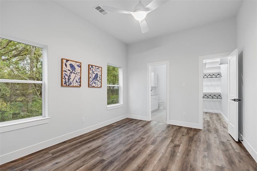 Unfurnished bedroom with ceiling fan, hardwood / wood-style floors, and multiple windows