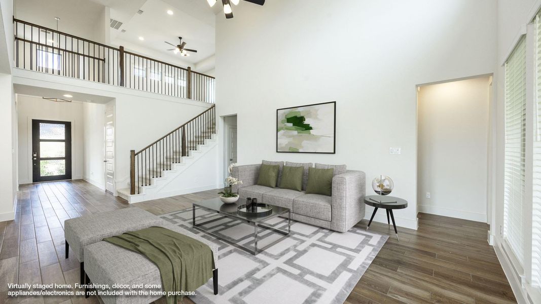 Living area with a towering ceiling, wood finished floors, ceiling fan, stairway, and recessed lighting
