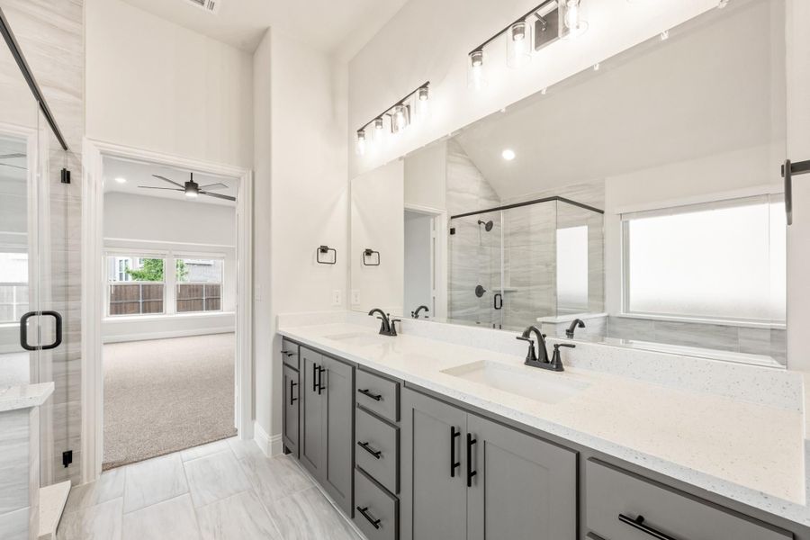 Master bathroom with double vanity, gray cabinets, quartz countertops, and glass shower enclosure Master bathroom with double vanity, gray cabinets, quartz countertops, and glass shower enclosure